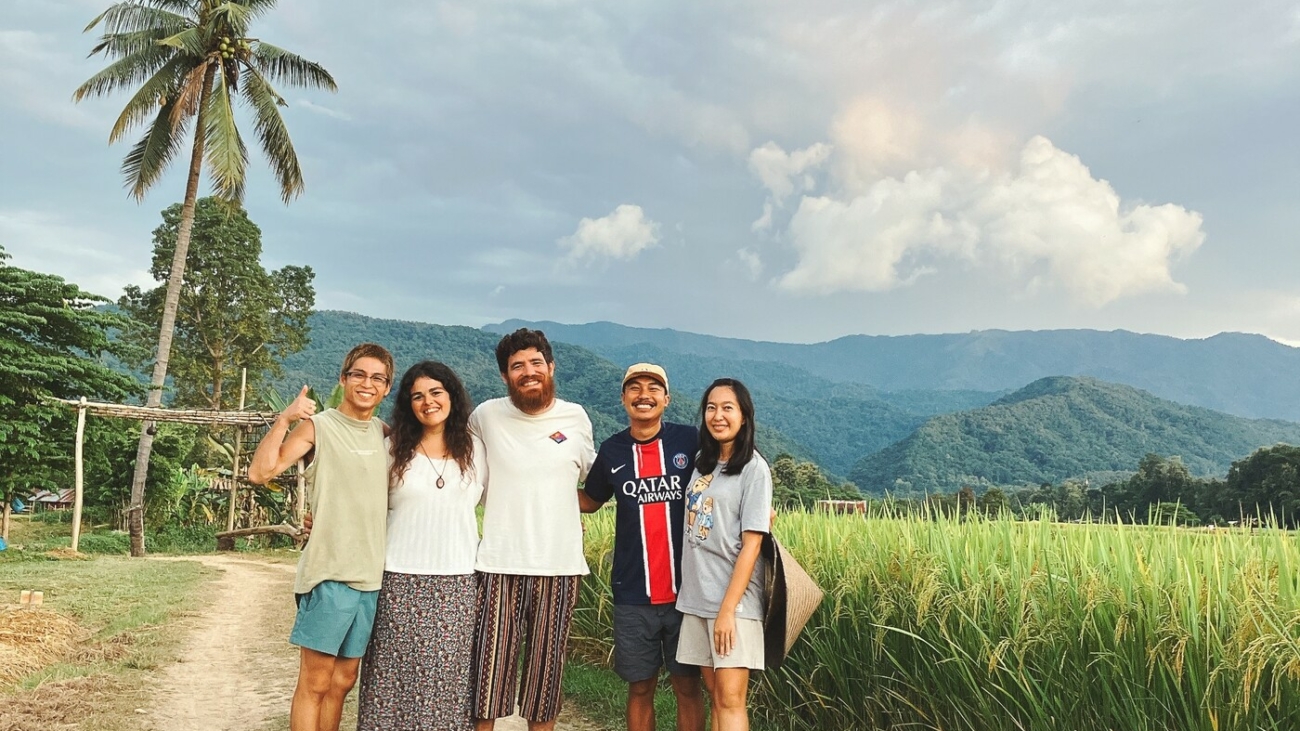 Martina e Lorenzo del progetto Giro.vagamondi, assieme ad alcuni amici conosciuti durante un Workaway autentico e sostenibile in Thailandia, davanti a campi di riso