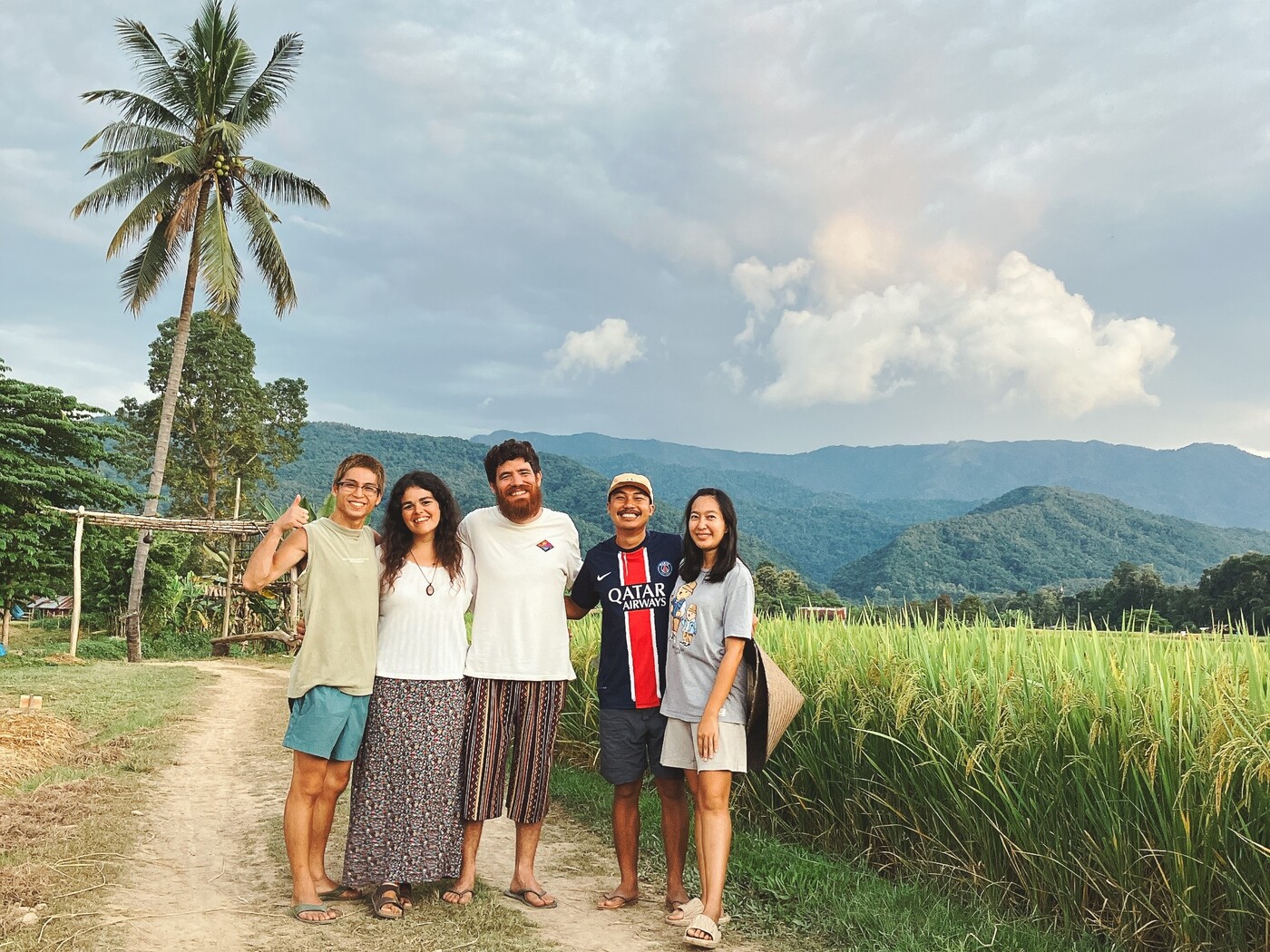 Martina e Lorenzo del progetto Giro.vagamondi, assieme ad alcuni amici conosciuti durante un Workaway autentico e sostenibile in Thailandia, davanti a campi di riso